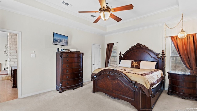 carpeted bedroom with ceiling fan, crown molding, and a tray ceiling