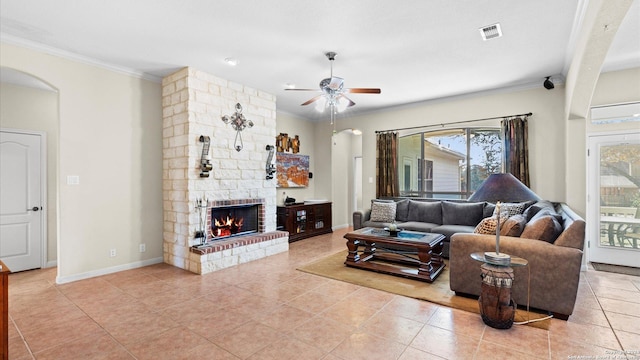 tiled living room with ceiling fan, crown molding, and a fireplace