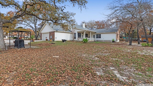 rear view of property featuring a gazebo, a porch, and a garage