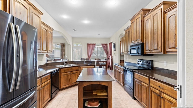 kitchen with sink, light tile patterned floors, decorative light fixtures, a kitchen island, and black appliances