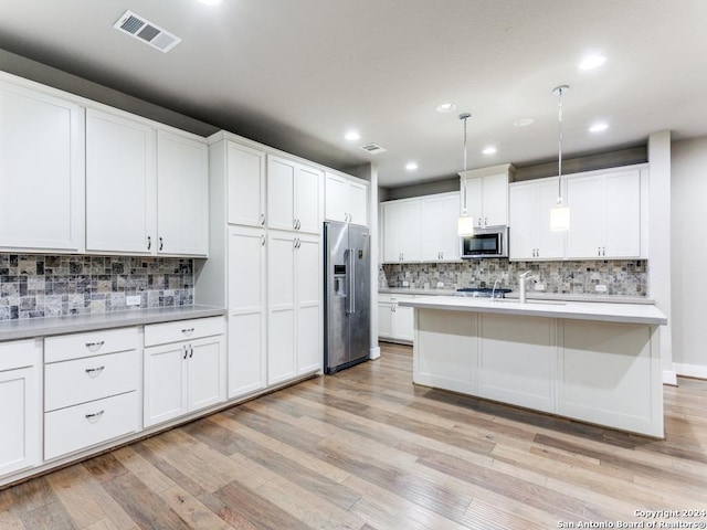 kitchen featuring white cabinets, stainless steel appliances, and hanging light fixtures