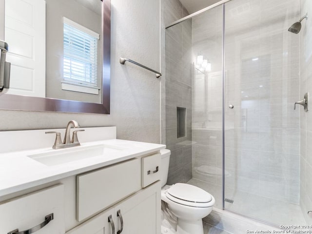 bathroom with toilet, a shower with door, and vanity