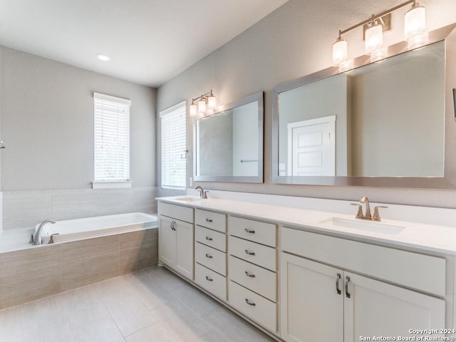 bathroom with tile patterned floors, tiled tub, and vanity