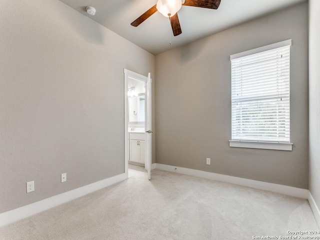 unfurnished bedroom featuring ceiling fan, light colored carpet, and ensuite bathroom