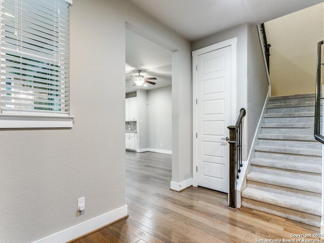 stairway featuring ceiling fan and wood-type flooring