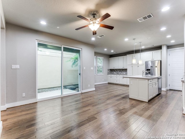 kitchen featuring decorative light fixtures, white cabinetry, tasteful backsplash, a kitchen island with sink, and appliances with stainless steel finishes