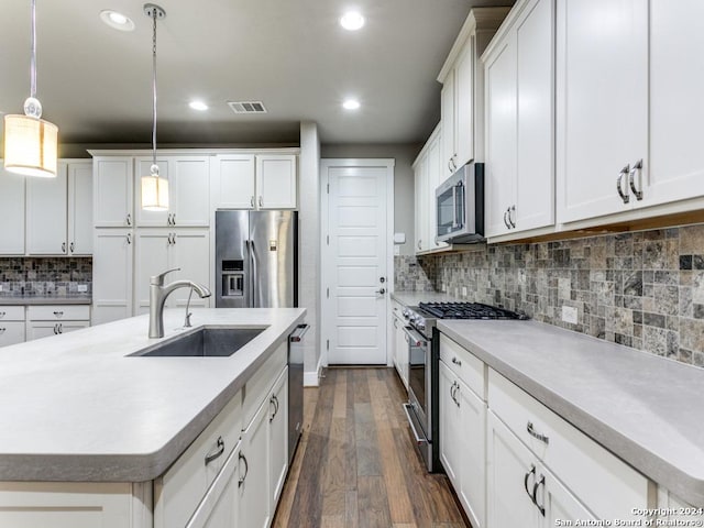 kitchen with decorative light fixtures, white cabinets, appliances with stainless steel finishes, and sink