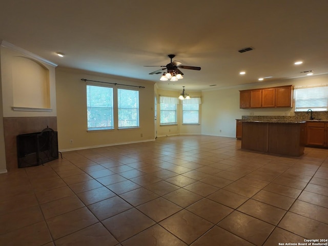 unfurnished living room with tile patterned flooring, ceiling fan with notable chandelier, crown molding, and sink