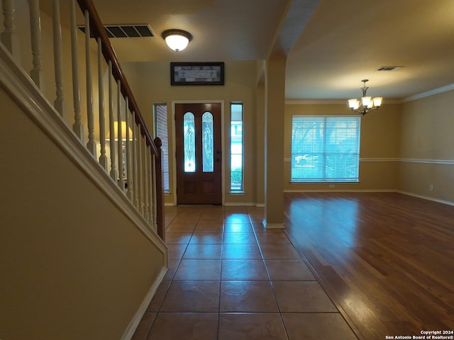 tiled foyer entrance with crown molding and an inviting chandelier