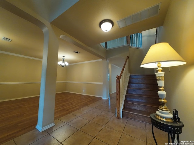 staircase featuring tile patterned floors, crown molding, and a chandelier