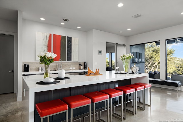 kitchen featuring a breakfast bar area, decorative backsplash, a wealth of natural light, and white cabinets