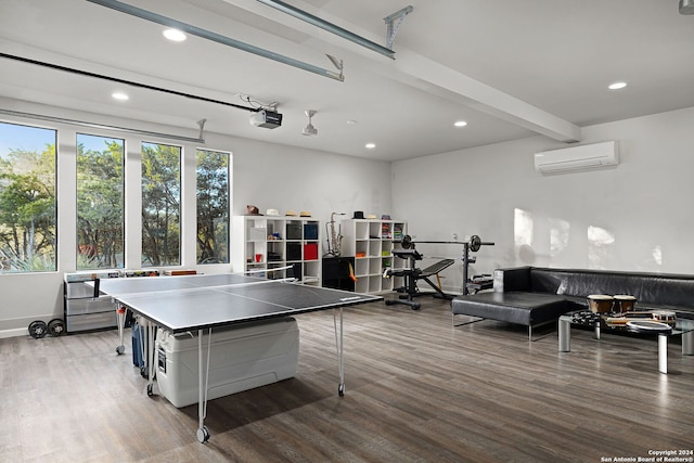 game room with beamed ceiling, wood-type flooring, and an AC wall unit