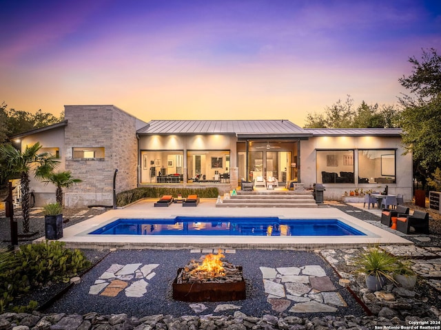 pool at dusk with a patio area and an outdoor fire pit