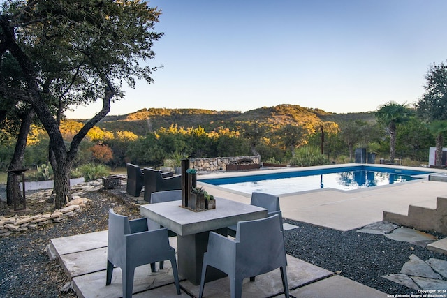 view of pool featuring a fire pit, a mountain view, and a patio