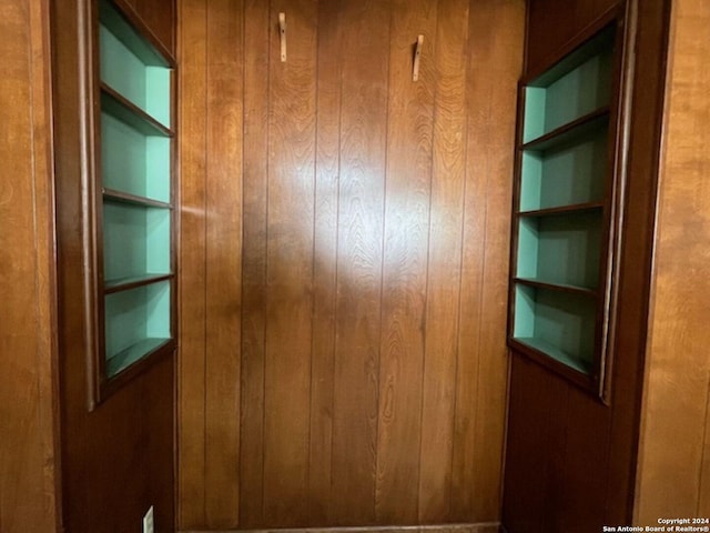 interior space featuring built in shelves and wooden walls