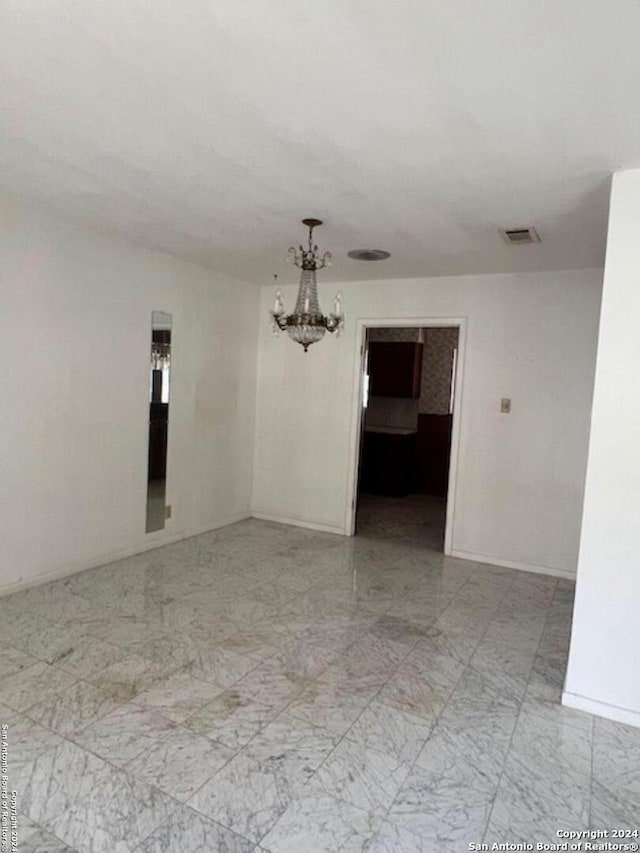 unfurnished room featuring an inviting chandelier