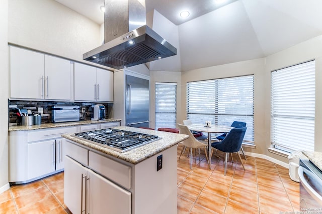 kitchen with white cabinetry, stainless steel appliances, lofted ceiling, island range hood, and light tile patterned floors