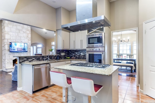 kitchen with a kitchen bar, appliances with stainless steel finishes, a healthy amount of sunlight, and ventilation hood