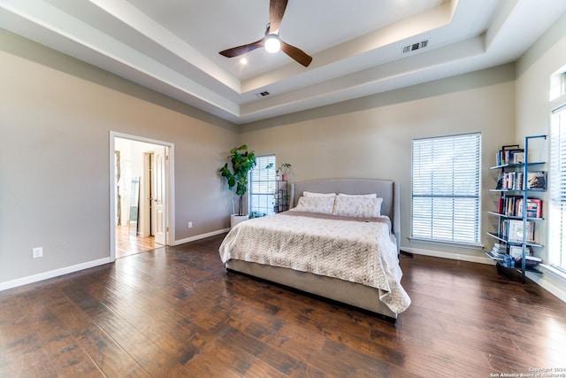 bedroom with a tray ceiling, ceiling fan, and dark hardwood / wood-style floors