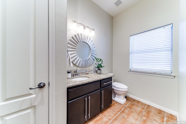 bathroom with toilet, vanity, and tile patterned floors