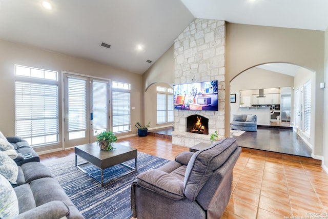 tiled living room with a stone fireplace and high vaulted ceiling