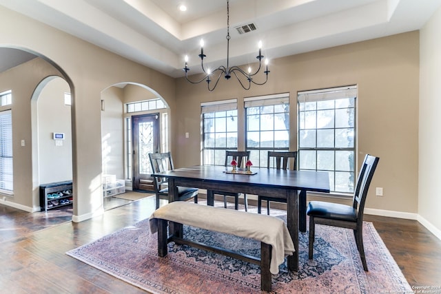 dining space featuring dark hardwood / wood-style flooring, a tray ceiling, and a chandelier