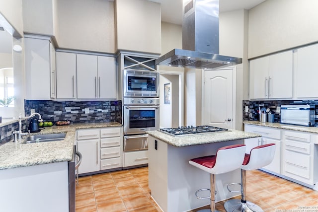 kitchen featuring a center island, white cabinets, sink, wall chimney exhaust hood, and appliances with stainless steel finishes