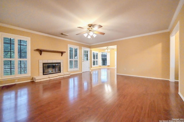 unfurnished living room with a tiled fireplace, crown molding, dark hardwood / wood-style flooring, and ceiling fan