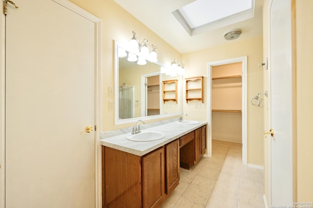 bathroom featuring tile patterned flooring, vanity, walk in shower, and a skylight