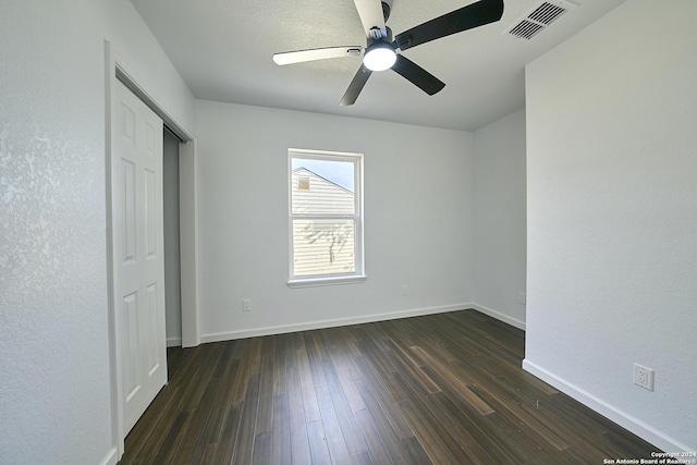 unfurnished bedroom featuring dark wood-type flooring, ceiling fan, and a closet