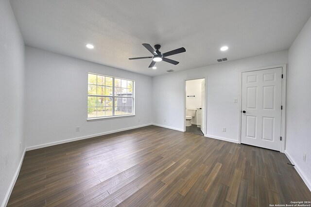 unfurnished bedroom with connected bathroom, dark wood-type flooring, and ceiling fan