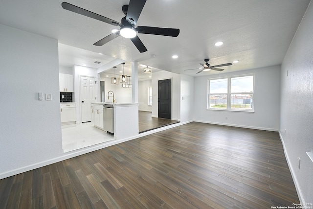 unfurnished living room featuring dark hardwood / wood-style flooring, sink, and ceiling fan