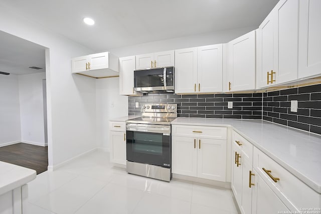 kitchen featuring appliances with stainless steel finishes, backsplash, light stone counters, white cabinets, and light tile patterned flooring