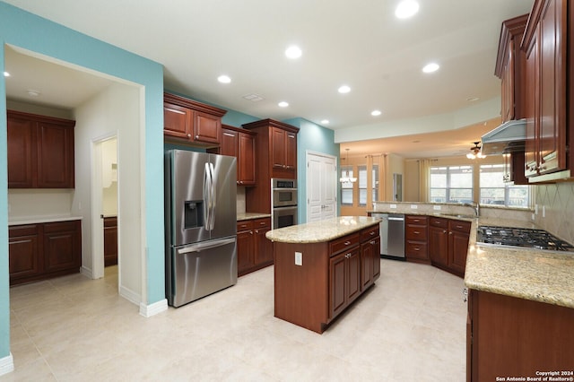 kitchen with a center island, sink, ceiling fan, light stone countertops, and appliances with stainless steel finishes