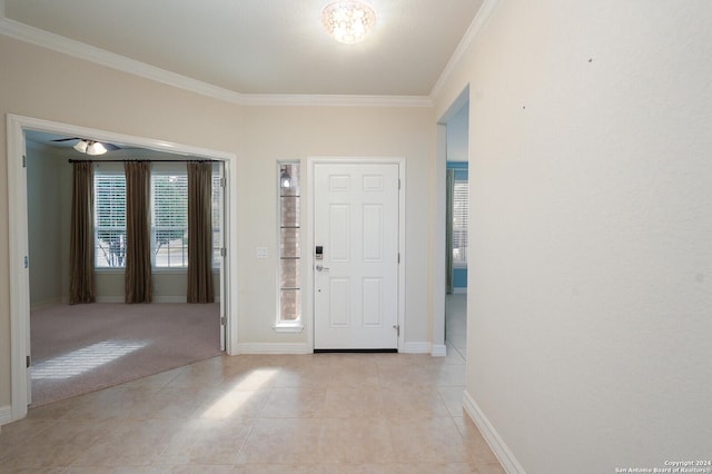 foyer entrance with light colored carpet, plenty of natural light, and crown molding