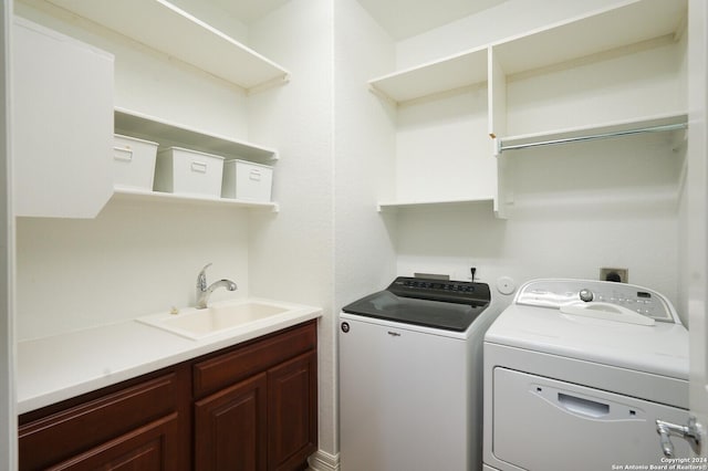 washroom with cabinets, independent washer and dryer, and sink