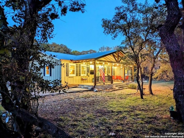 back of property with board and batten siding, covered porch, and metal roof