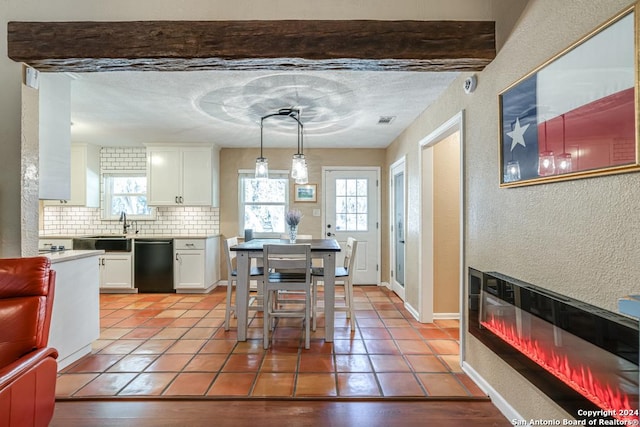 dining space with a glass covered fireplace, a textured wall, baseboards, and light tile patterned floors