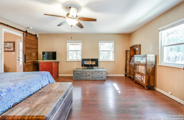 bedroom with a barn door, baseboards, and dark wood finished floors