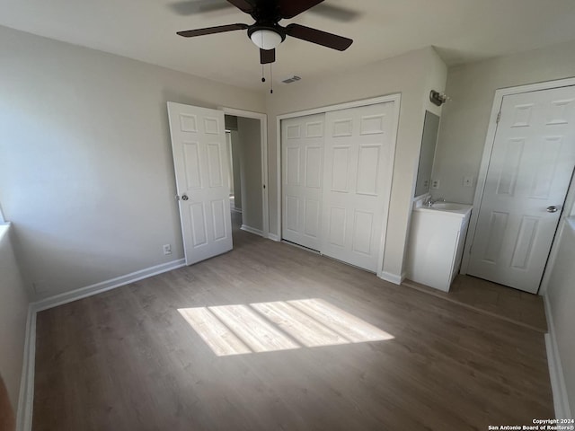 unfurnished bedroom featuring hardwood / wood-style flooring, ceiling fan, and sink