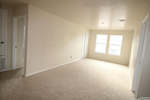 carpeted empty room with a textured ceiling