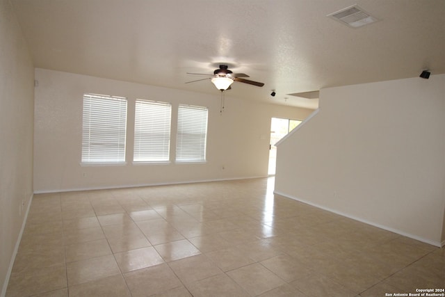 tiled spare room featuring a wealth of natural light and ceiling fan