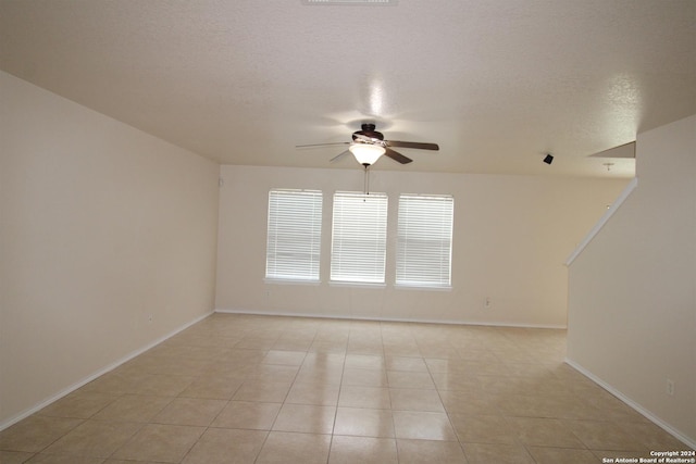 tiled empty room with ceiling fan and a textured ceiling