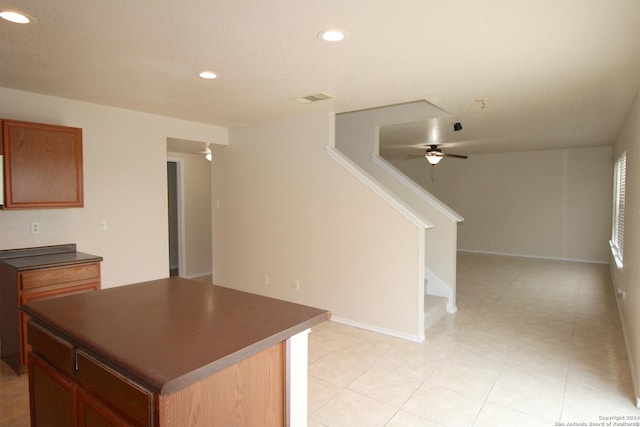 kitchen featuring ceiling fan, a kitchen island, and light tile patterned flooring