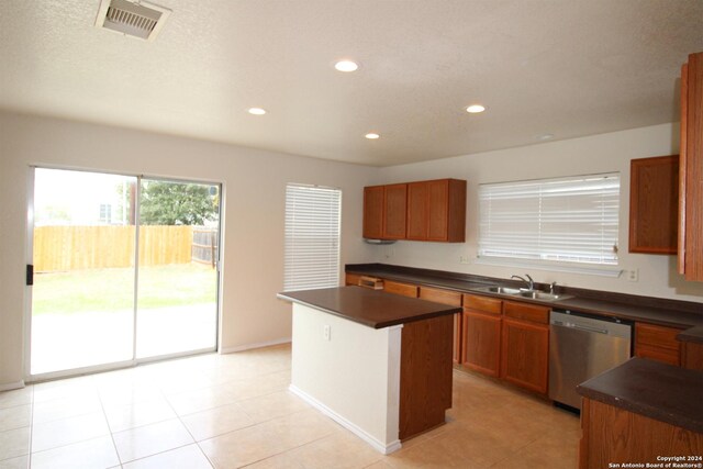 kitchen with dishwasher, a center island, light tile patterned floors, and sink