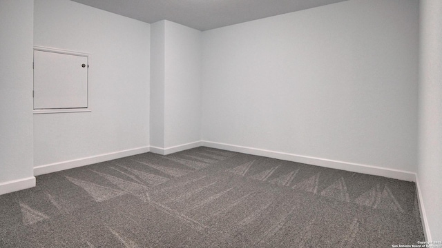 empty room with dark carpet and baseboards