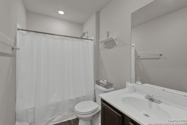 full bathroom featuring hardwood / wood-style flooring, vanity, toilet, and shower / bath combo