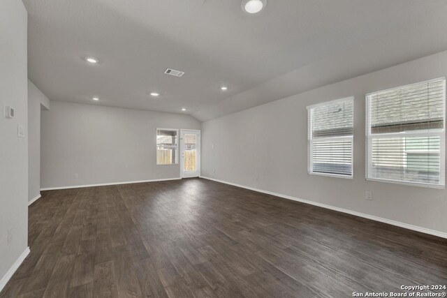 unfurnished room featuring lofted ceiling and dark hardwood / wood-style floors