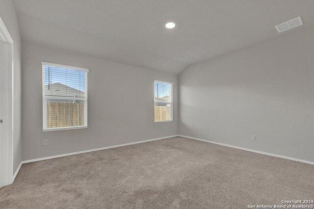 unfurnished room with vaulted ceiling and light colored carpet