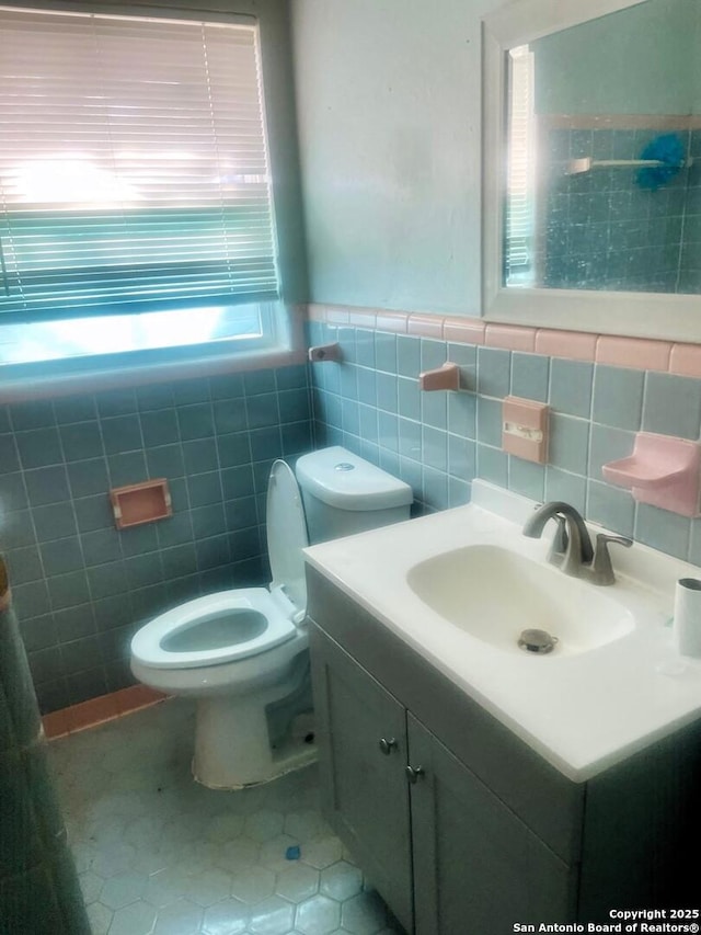 bathroom featuring tile patterned floors, vanity, toilet, and tile walls